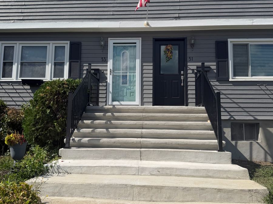 After: new concrete front steps with black railings on a Dorchester two-family