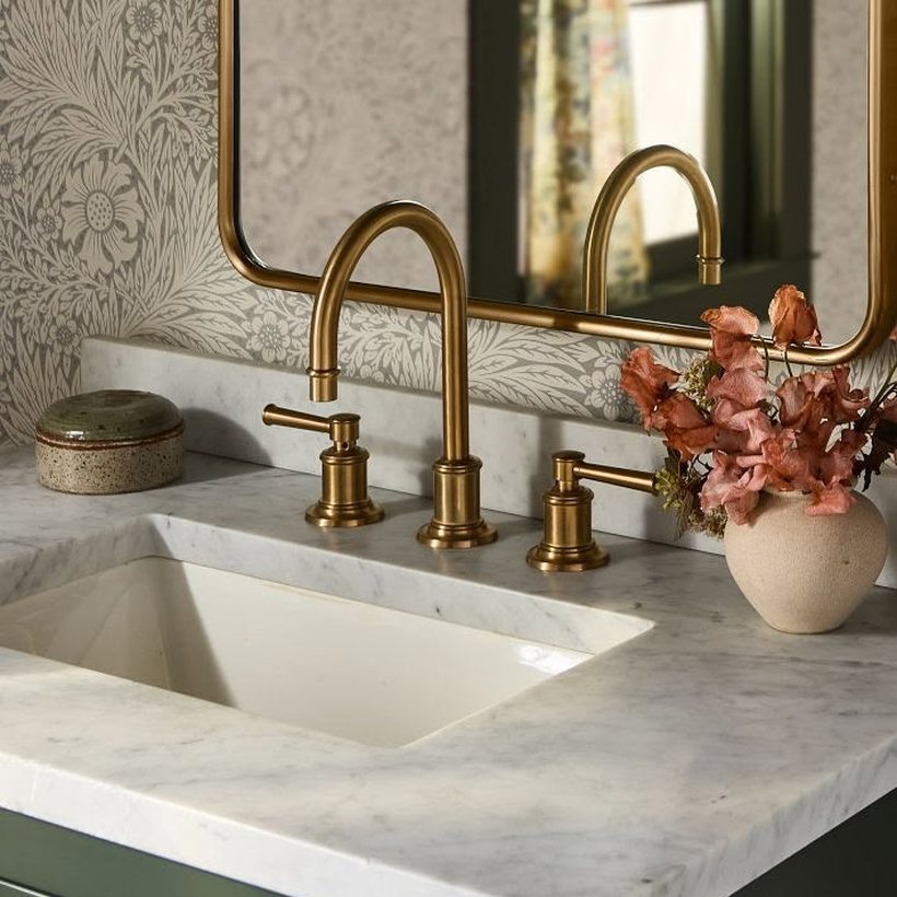 Bathroom vanity detail with brass faucet and marble countertop