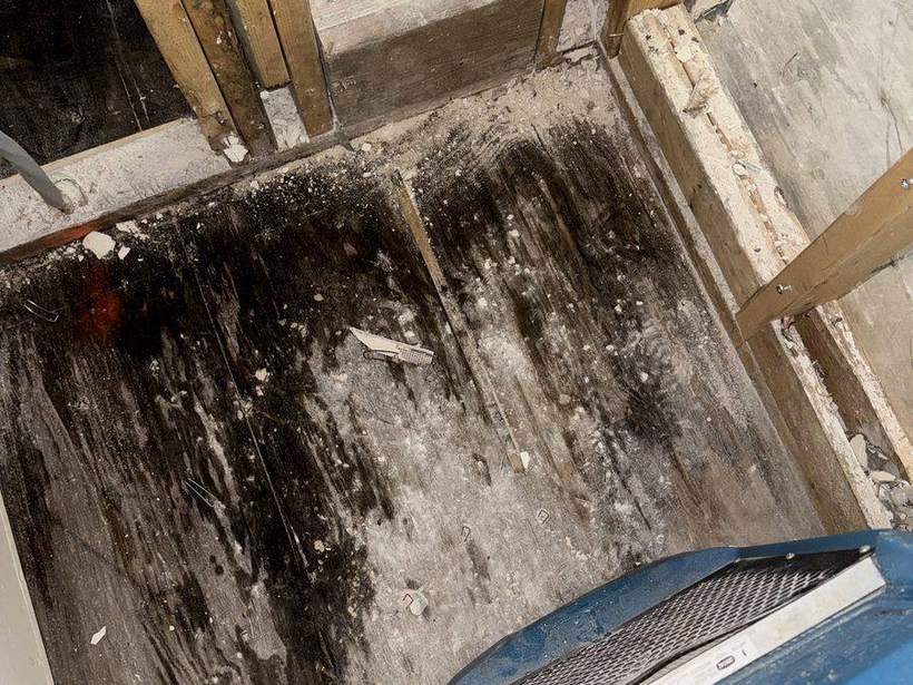 Air mover drying a water-stained subfloor after demolition