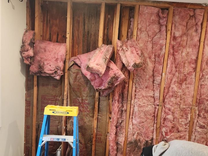 Before: the bedroom wall opened, wet insulation exposed