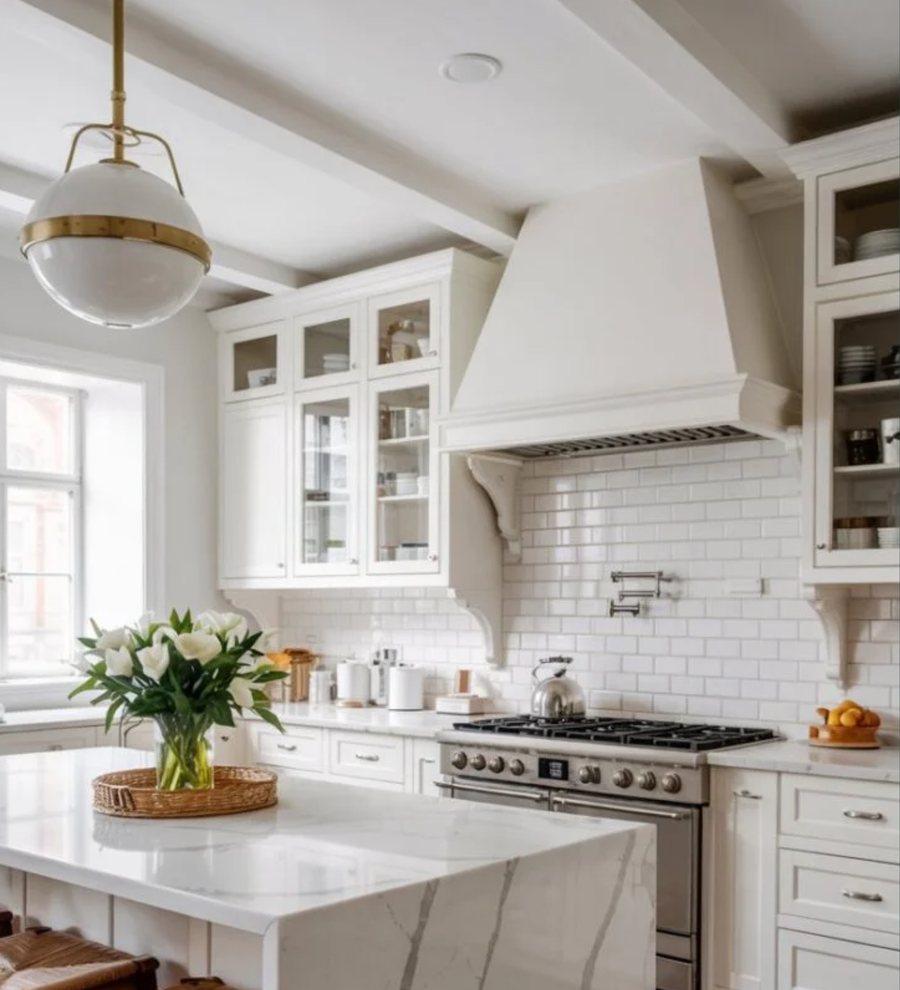 Bright white kitchen with marble waterfall island, subway tile, and brass pendant