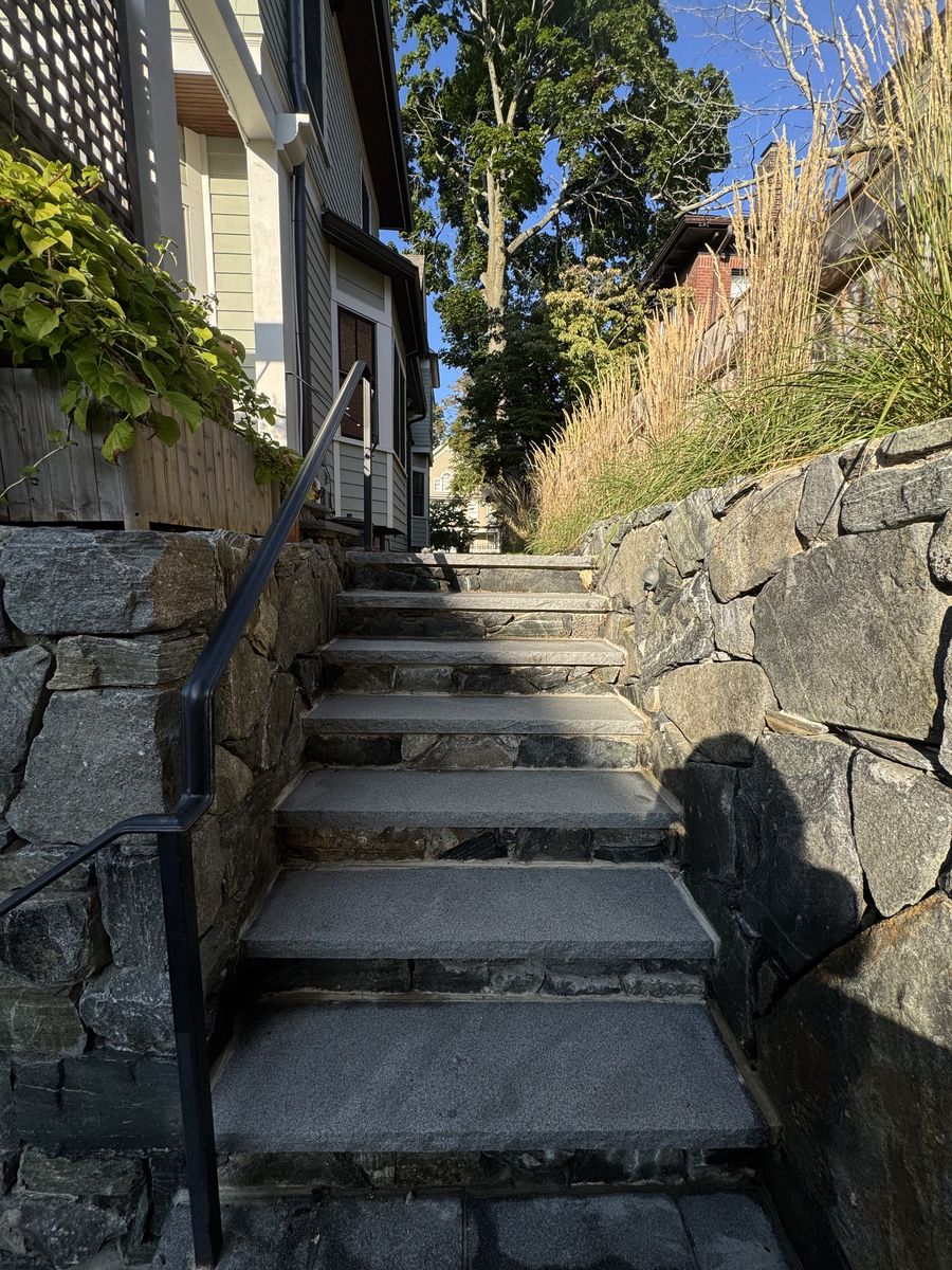 Granite steps between fieldstone walls up a side yard in Brookline