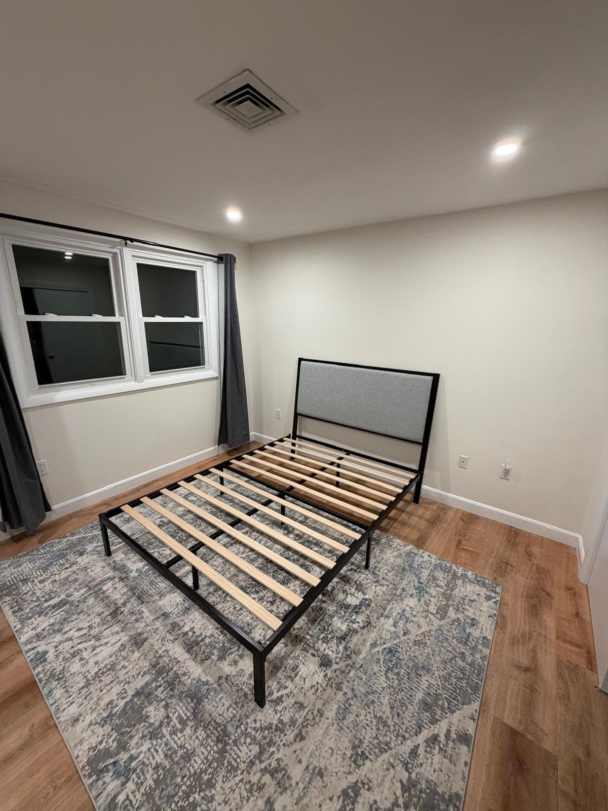 After: West Roxbury bedroom fully restored with new drywall, paint, flooring, and bed frame — completed restoration by SR Enterprises