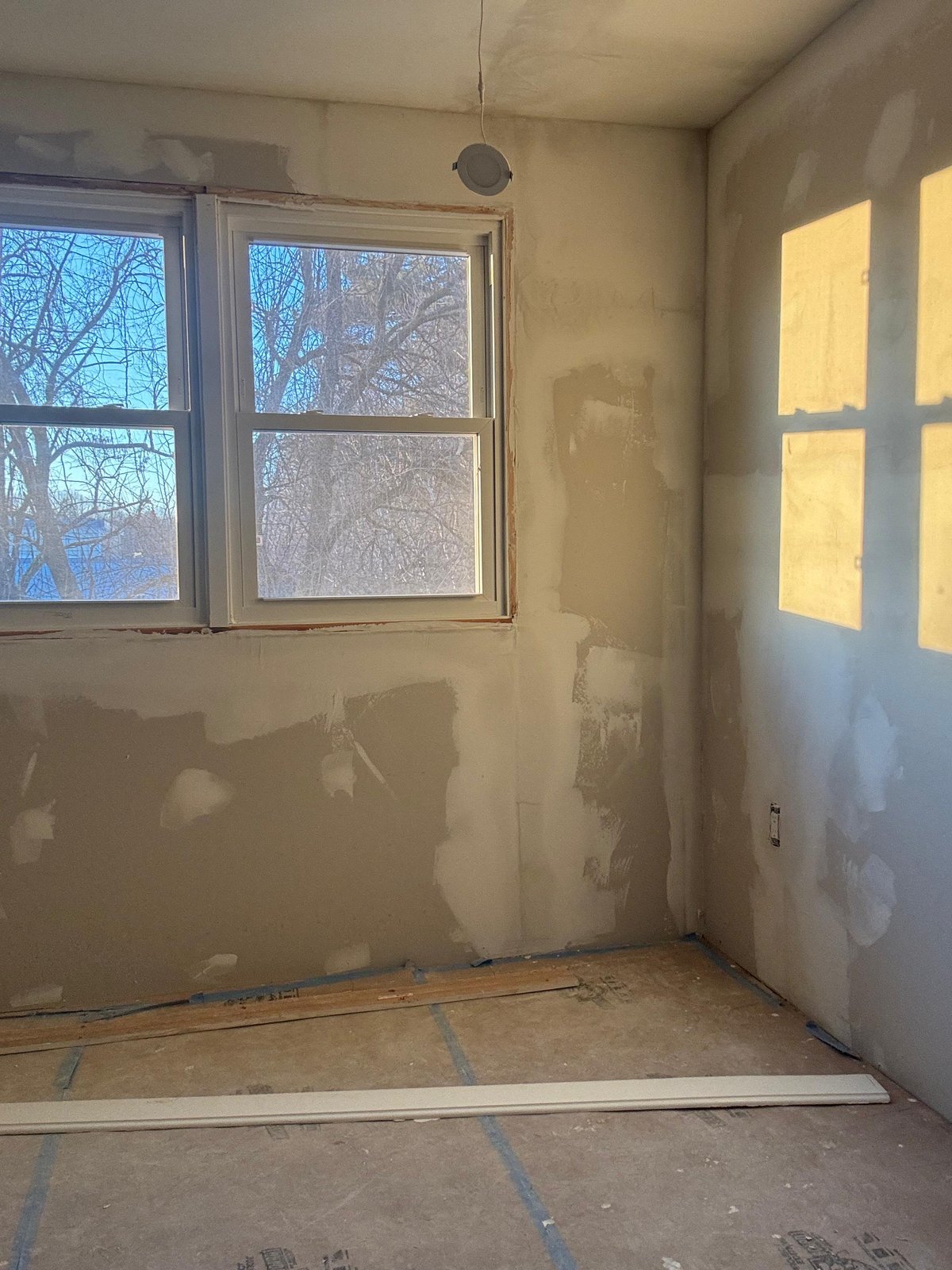 Bedroom mid-restoration in West Roxbury MA showing primed drywall and recessed lighting installed — SR Enterprises