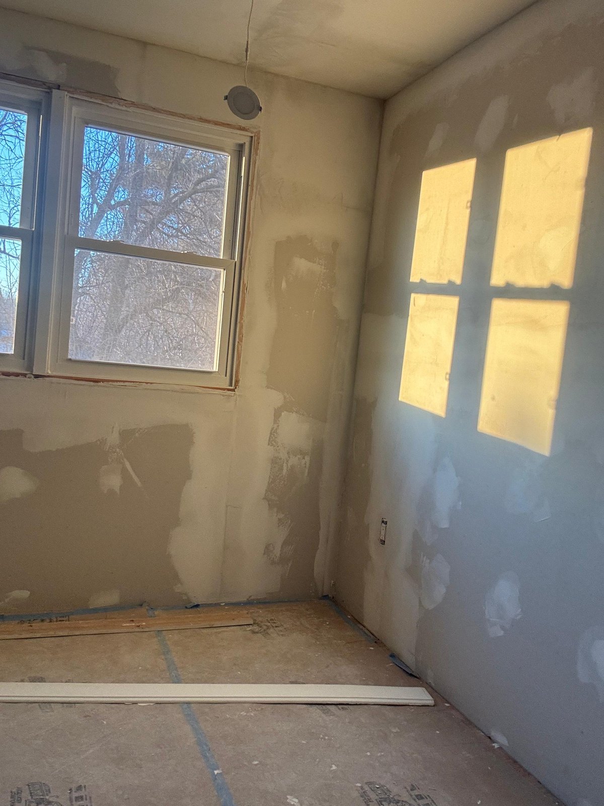 West Roxbury bedroom window mid-restoration showing primed walls and protected floors — SR Enterprises